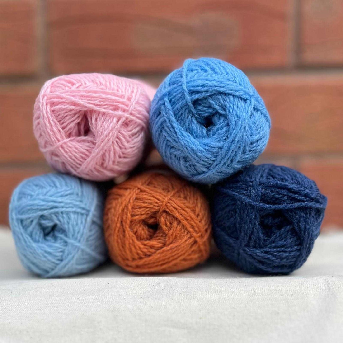 5 balls of yarn in shades of pink, blue and orange