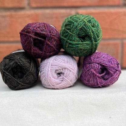 5 balls of yarn in shades of black, pink and green